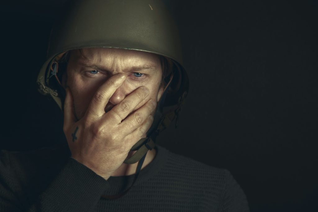 a man wearing a helmet covers his face with his hands